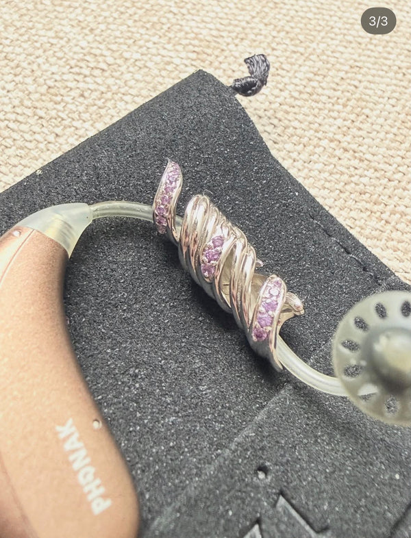 Robyn C.'s silver HEARLOOM jewellery with purple gemstones fitted to a Phonak hearing aid, on Auzi packaging